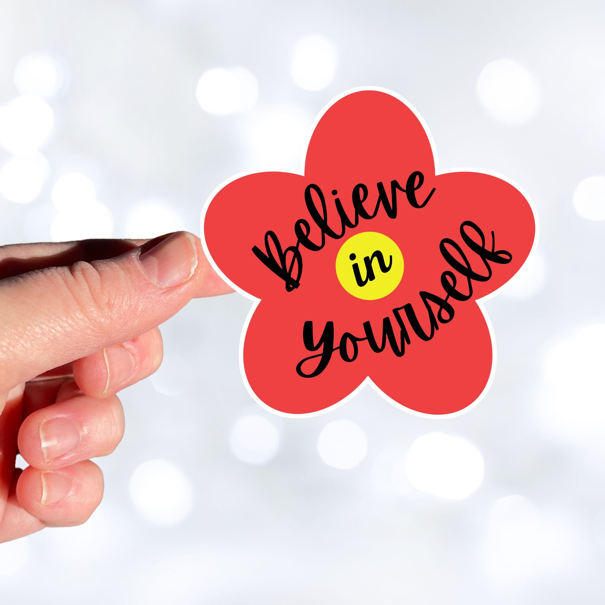 This inspirational individual die-cut sticker features a red flower with a yellow center, with the words Believe in Yourself written across it. Check out our Inspirational collection for more inspiring stickers! This image shows a hand holding the Believe in Yourself sticker.