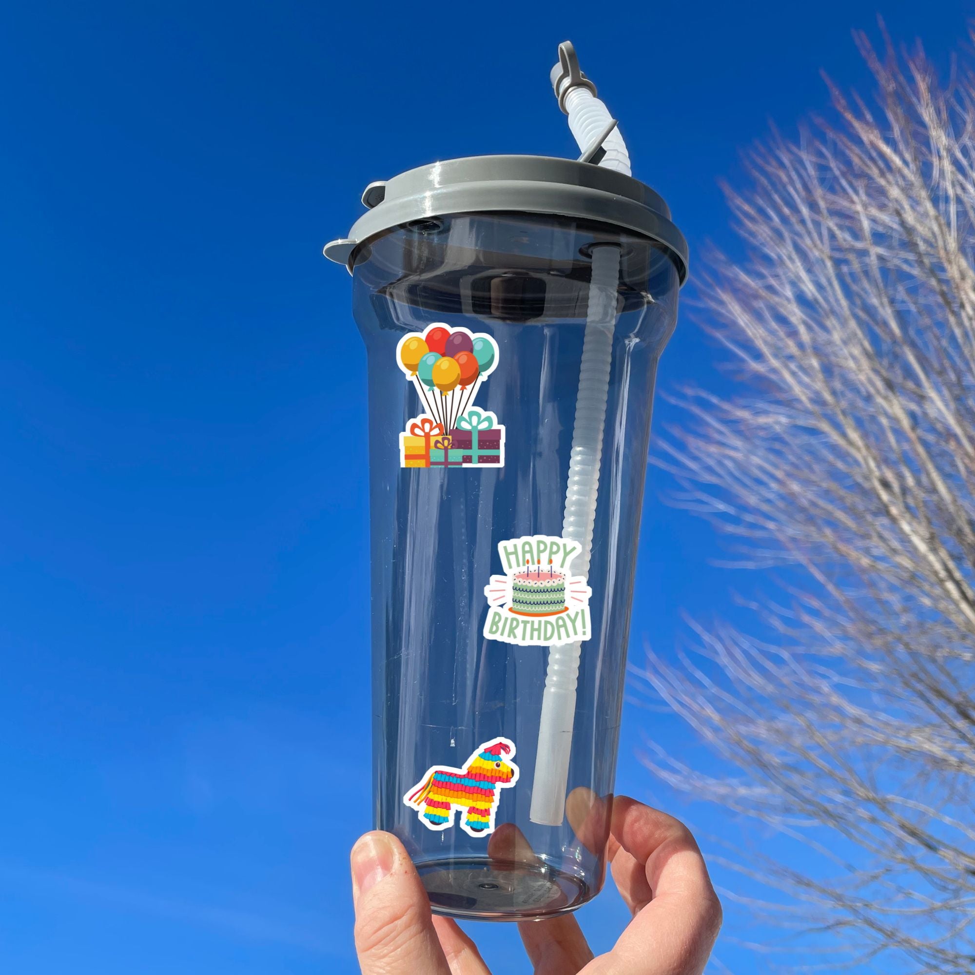 This birthday sticker sheet has a sparkle overlay with stickers showing all your favorite birthday celebration items like: Birthday cakes, presents, balloons, a piñata, birthday hats, and streamers. This image is of a water bottle with a birthday cake, presents and balloons, and a piñata on it. 