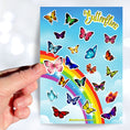 Load image into Gallery viewer, With over 20 butterfly stickers, this sticker sheet will be a sure hit with anyone who loves butterflies! This image shows a hand holding a pink butterfly above the sticker sheet.
