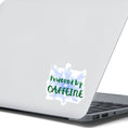 Load image into Gallery viewer, or those who like it, caffeine can be the magic elixir! This individual die-cut sticker has the words Powered by CAFFEINE in green over a background of blue electric/lightning bolts. This image shows the Powered by Caffeine sticker on the back of an open laptop.
