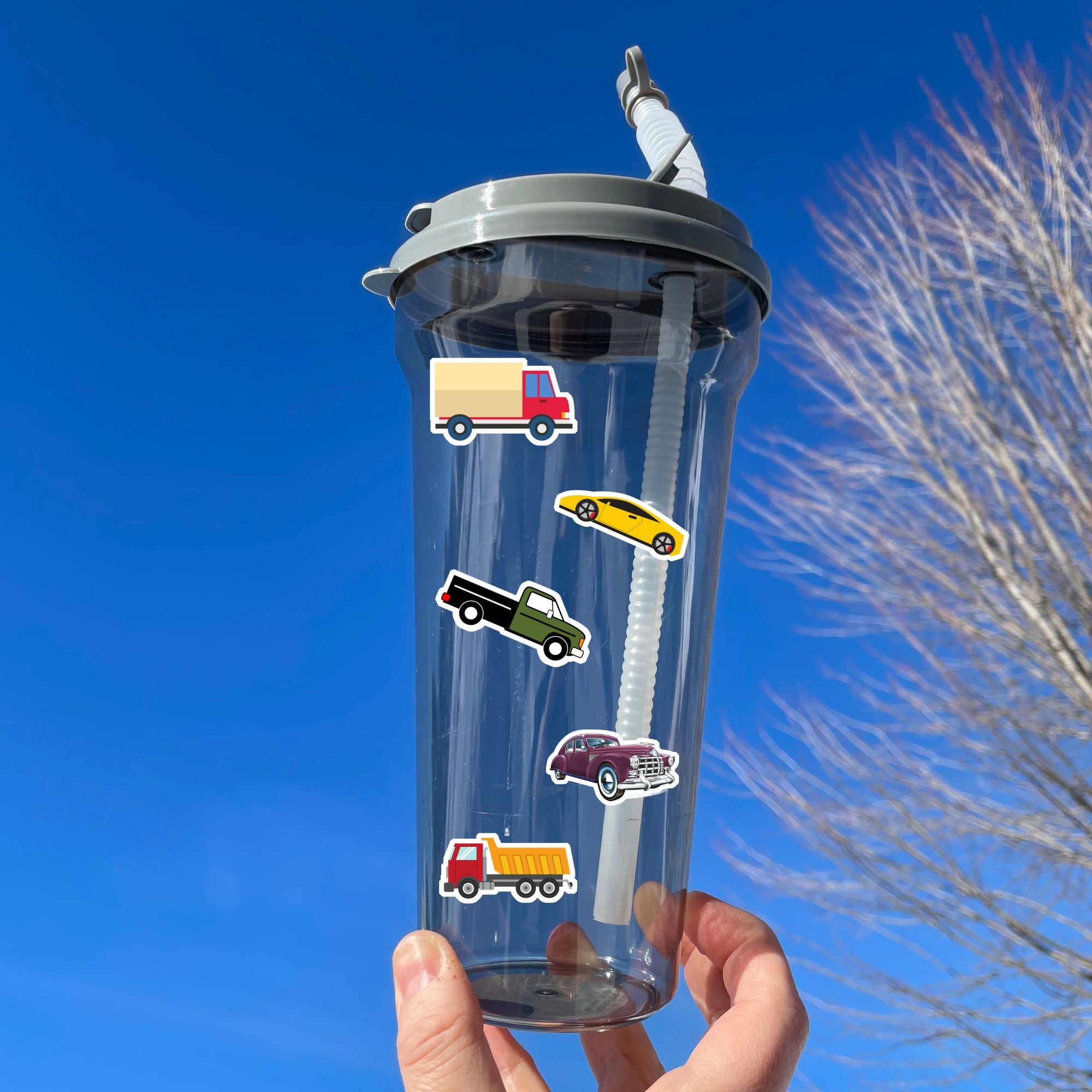 This sticker sheet has a collection of car and truck stickers; perfect for kids and adults who like their four wheel friends! This sheet has six different car stickers and six different truck stickers on a green and blue background. This image shows a water bottle with three trucks and two cars applied to it.