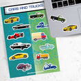 Load image into Gallery viewer, This sticker sheet has a collection of car and truck stickers; perfect for kids and adults who like their four wheel friends! This sheet has six different car stickers and six different truck stickers on a green and blue background. This image shows the sticker sheet next to a laptop with one car and one truck sticker applied below the keyboard.
