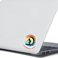 Load image into Gallery viewer, Hang 10 Bro! Catch a wave with this individual die-cut sticker featuring the silhouette of a female surfer inside the tube, all on a colored gradient background. Cowabunga! This image shows the Catching a Wave sticker on the back of an open laptop.
