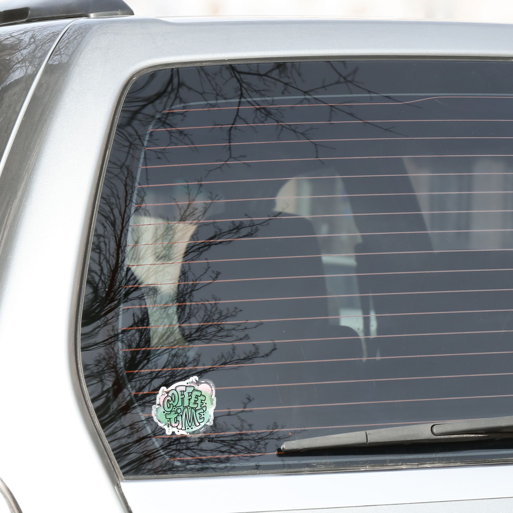 It's Coffee Time! This individual die-cut sticker features the words Coffee Time over a pastel green and pink background. This coffee sticker is great for all coffee lovers! This image shows the Coffee Time sticker on the back window of a car.