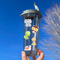 Load image into Gallery viewer, This sticker sheet has a sparkle overlay and it features stickers of cute baby animals from a bear to a zebra, with birds, lions, a monkey, and even snakes and snails in between. This image shows a water bottle with stickers of an elephant, owl, snake, giraffe, and snail attached to it.
