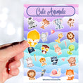 Load image into Gallery viewer, This sticker sheet has a sparkle overlay and it features stickers of cute baby animals from a bear to a zebra, with birds, lions, a monkey, and even snakes and snails in between. This image shows a hand holding a baby bird sticker above the sticker sheet.
