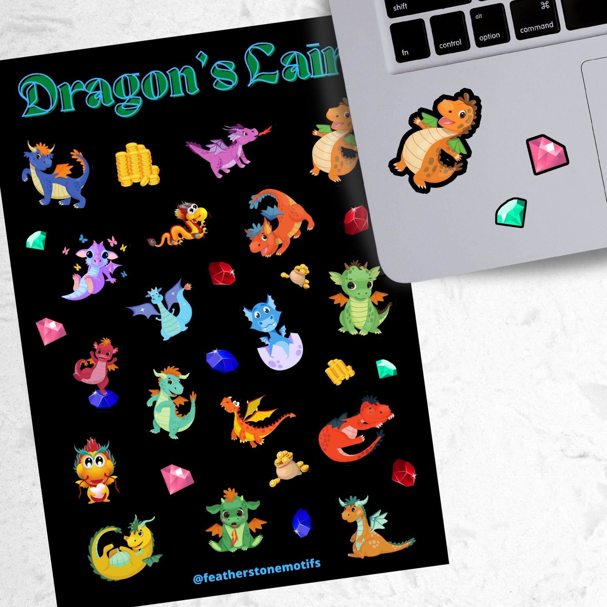 This sticker sheet is filled with cute images of baby dragons, and of course their treasure! This image shows the sticker sheet next to an open laptop with a sticker of an orange dragon with green wings and two gem stickers applied below the keyboard.