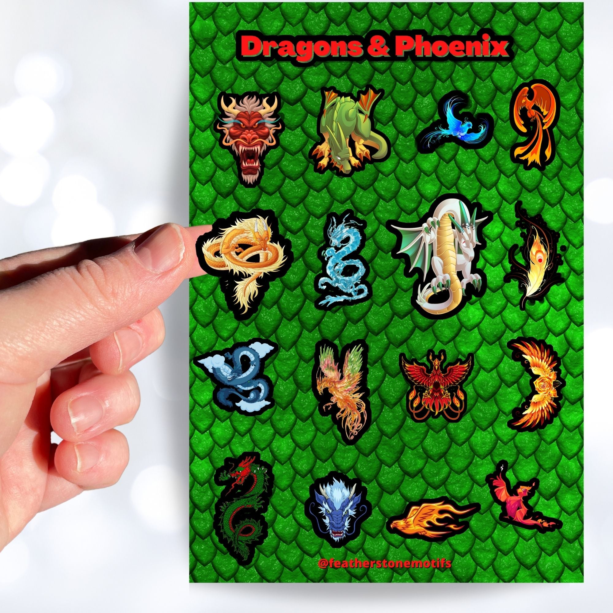 Set on a background of green scales, this sticker sheet has 16 different stickers of dragons and phoenix. This image shows a hand holding a feathery golden dragon above the sticker sheet.