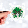 Load image into Gallery viewer, Drummer's, this individual die-cut sticker is for you! It features a drum kit on a green and gray paint splashed background. This drum sticker makes a great gift for anyone who loves to hit the skins. This image shows a hand holding the drum sticker.
