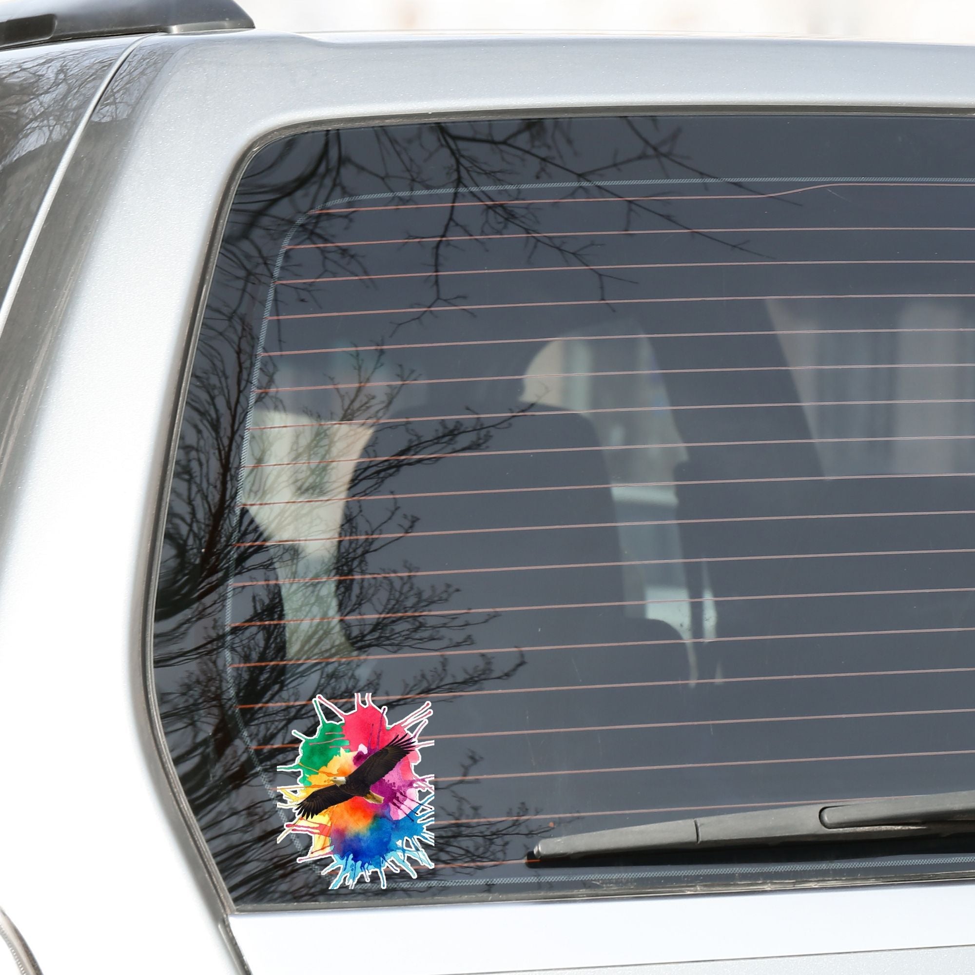 Soar with Eagles! This individual die-cut sticker features a majestic eagle soaring over a paint splash background. This image shows the Soaring Eagle sticker on the back window of a car.