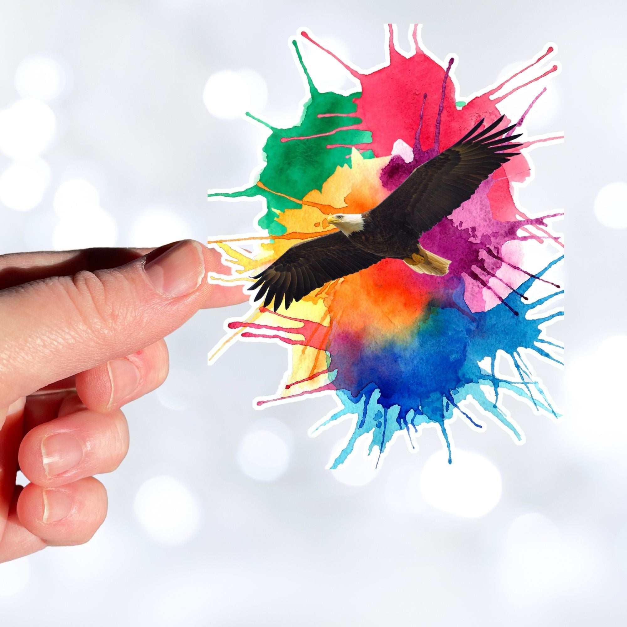 Soar with Eagles! This individual die-cut sticker features a majestic eagle soaring over a paint splash background. This image shows a  hand holding the Soaring Eagle sticker.