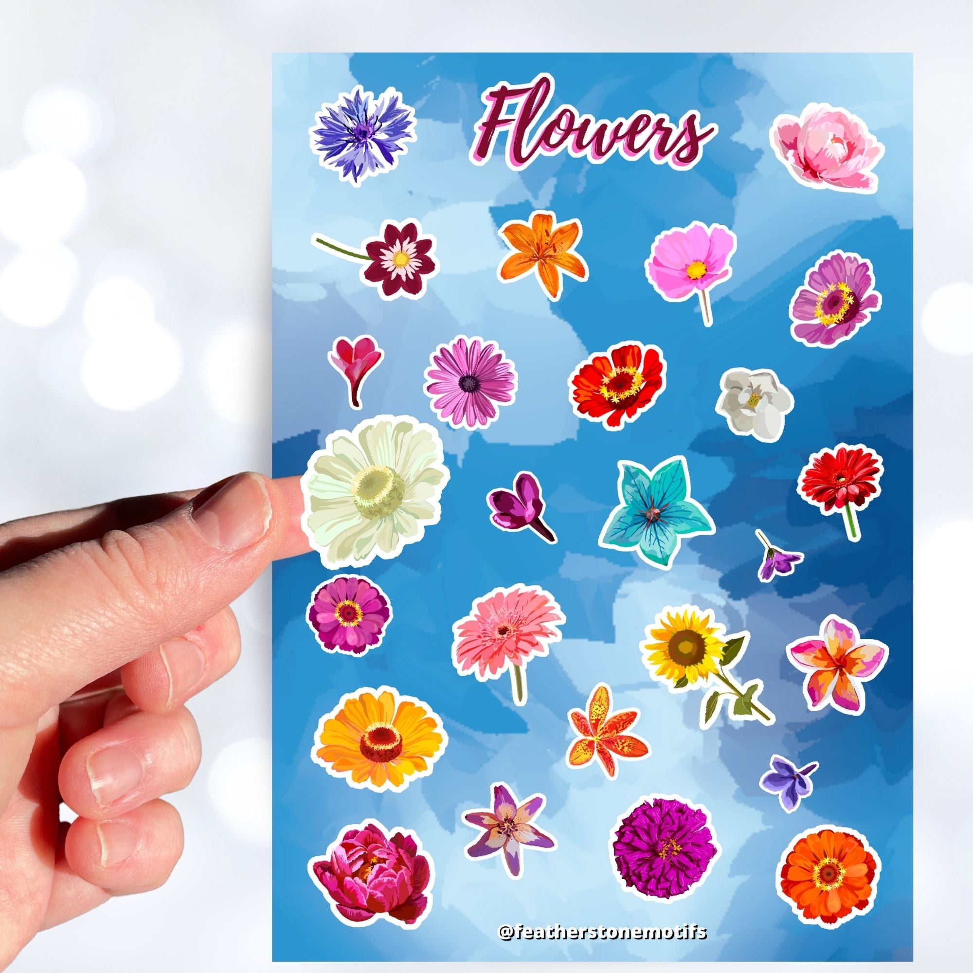 So many flowers! This sticker sheet is filled with images of all your favorite flowers. This image shows a hand holding a white flower above the sticker sheet.