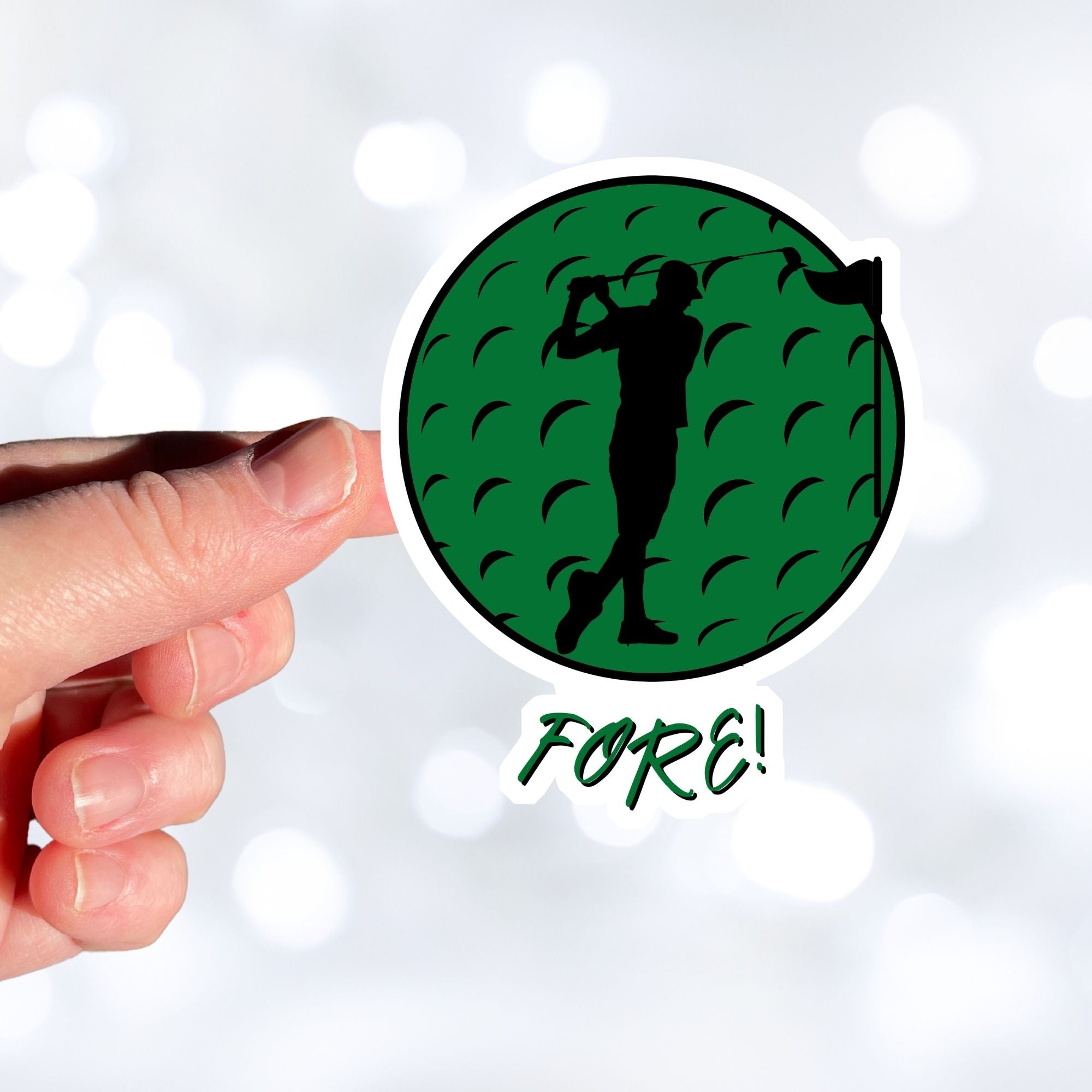 Show your love of golf with this individual die-cut sticker! This sticker shows the silhouette of a golfer about to swing, on a green golf ball background, with the word "Fore!" below.  This image is of a hand holding the golf sticker.