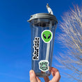 Load image into Gallery viewer, Set on a background of a circuit board, this sticker sheet is filled with futuristic sticker images like rocket ships, flying cars, aliens, and robots, and it has a holographic star overlay! This image shows a water bottle with the sticker sheet header reading "Futuristic", green alien head, and "The Future is Green" stickers applied to it.
