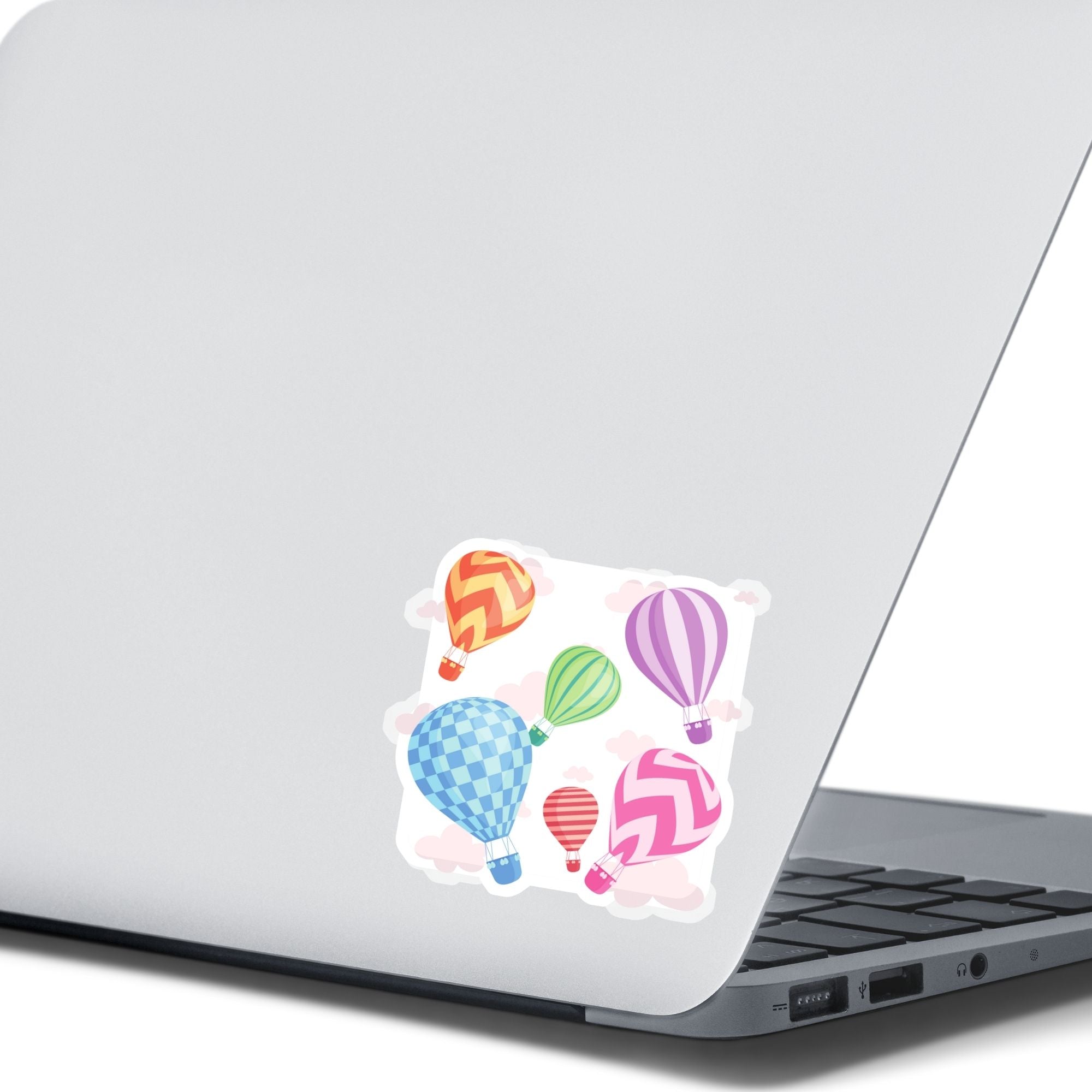 Float away on a colorful hot air balloon! This individual die-cut hot air balloon sticker has six, yes six, different hot air balloons on a background of clouds. This image shows the hot air balloon sticker on the back of an open laptop.