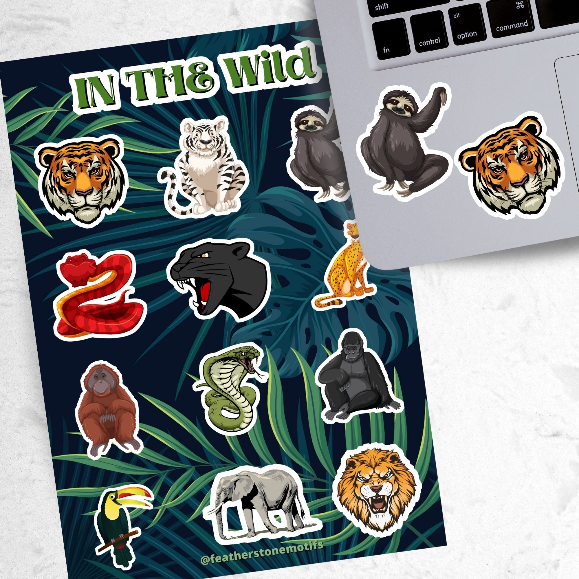 This sticker sheet has sticker images of your favorite jungle and rain forest creatures! There are a dozen different sticker images including tigers, a lion, a gorilla, snakes, and even a sloth.  This image shows the sticker sheet next to an open laptop with stickers of a sloth and a tiger head applied below the keyboard.
