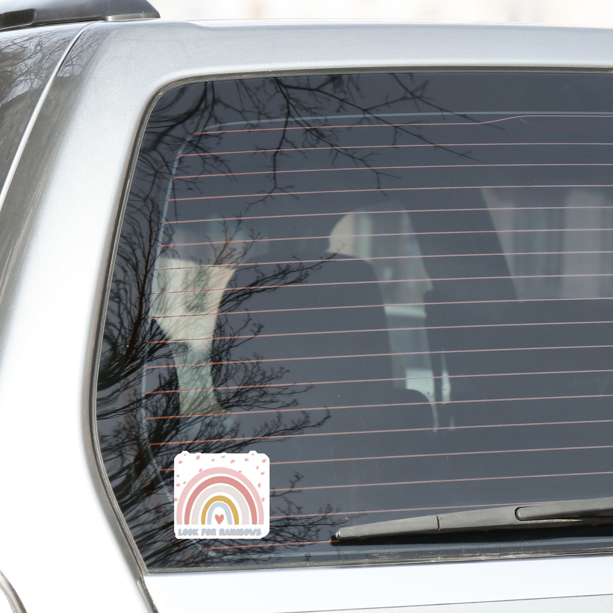 Look for Rainbows! This individual die-cut sticker features a pastel rainbow with "Look for Rainbows" written below. This image shows the Look for Rainbows sticker on the back window of a car.