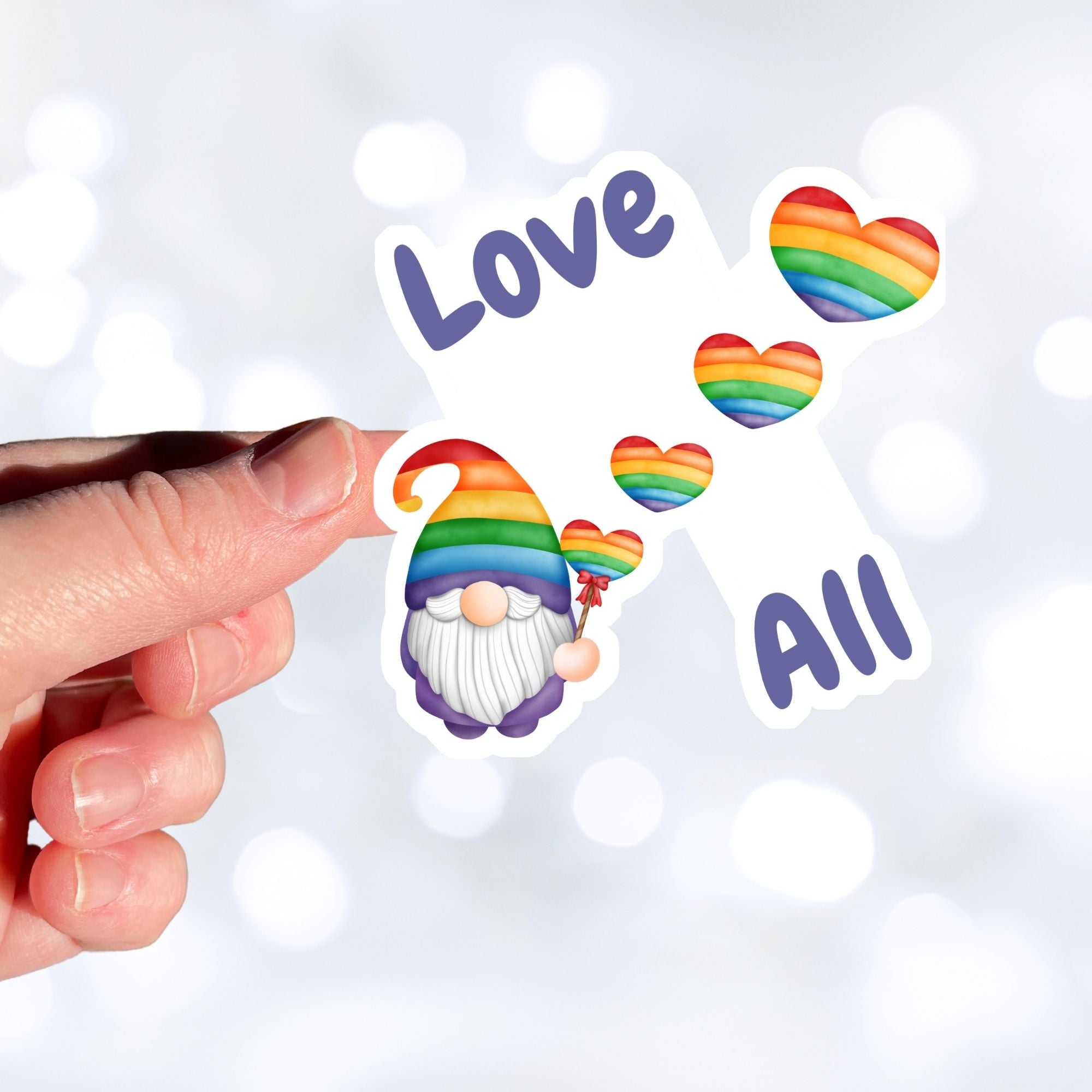 This gnome is showing his Pride! With the words "Love All", this individual die-cut sticker features a gnome with a rainbow hat and rainbow heart balloons. This image shows a hand holding the Gnome Love All sticker.