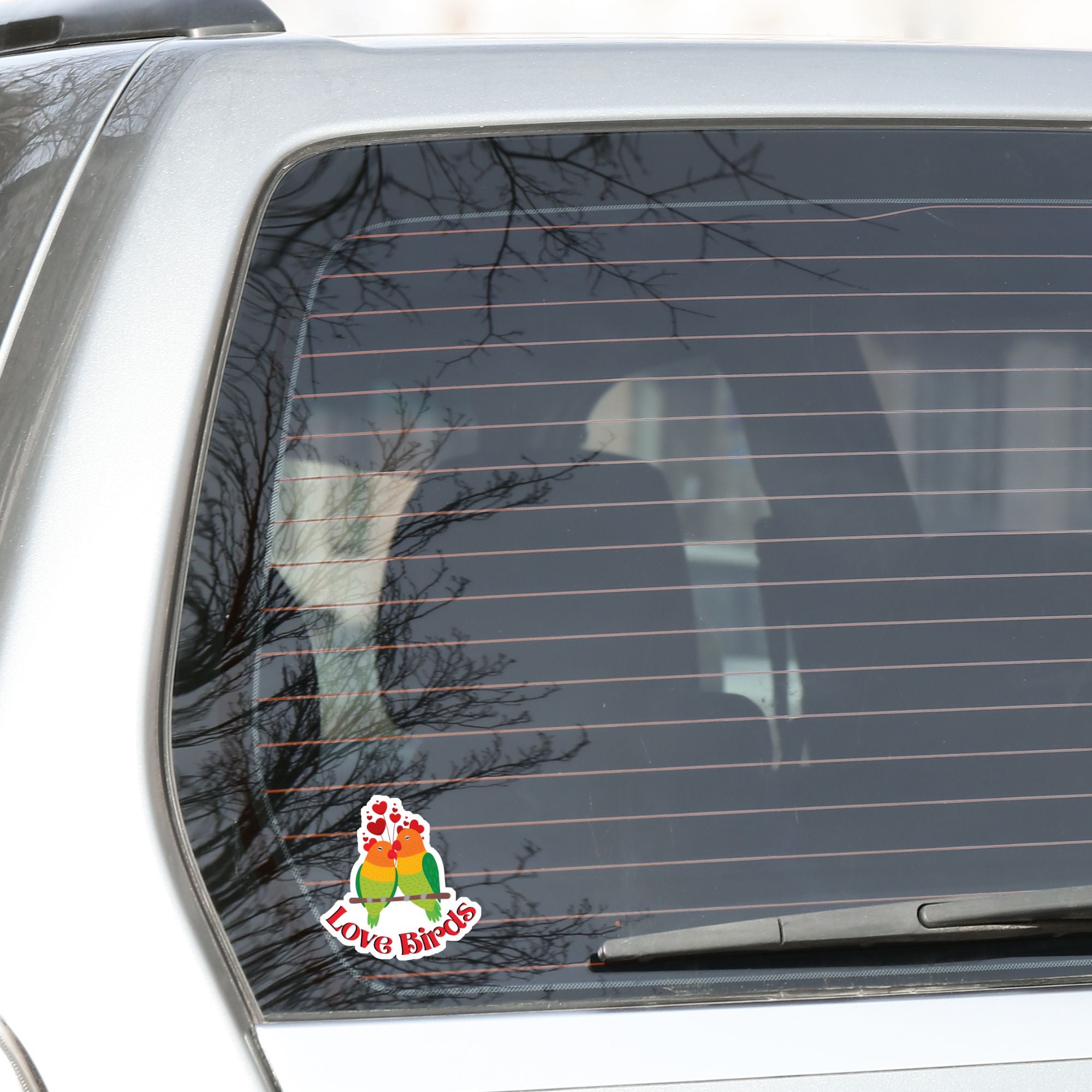 Aww, Love Birds! This individual die-cut sticker features a pair of love birds with hearts above. This is a perfect gift for your love bird! This image shows the Love Birds sticker on the back of a car.