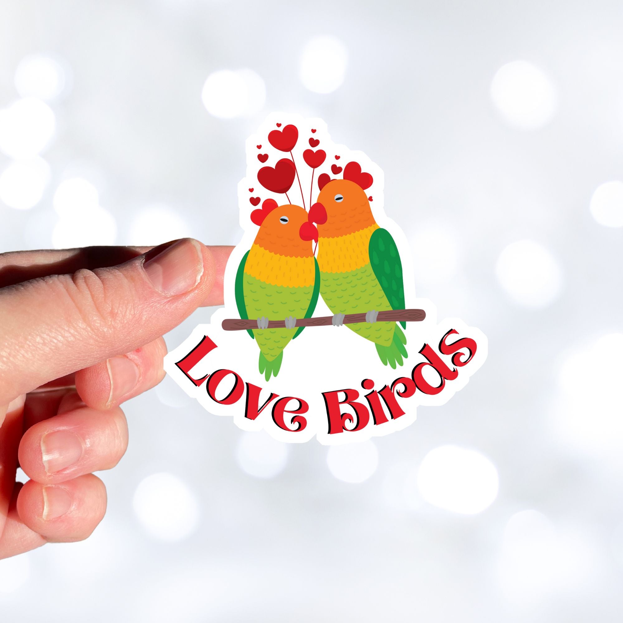 Aww, Love Birds! This individual die-cut sticker features a pair of love birds with hearts above. This is a perfect gift for your love bird! This image shows a hand holding the Love Birds sticker.