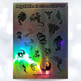 Load image into Gallery viewer, Dragons and Phoenix! This holographic sticker sheet is filled with images of mythical creatures; which are your favorites? 
