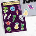 Load image into Gallery viewer, This sticker sheet is out of this world with individual stickers of aliens, space ships, planets, and alien creatures. This image is of a laptop with 2 of the stickers on it.
