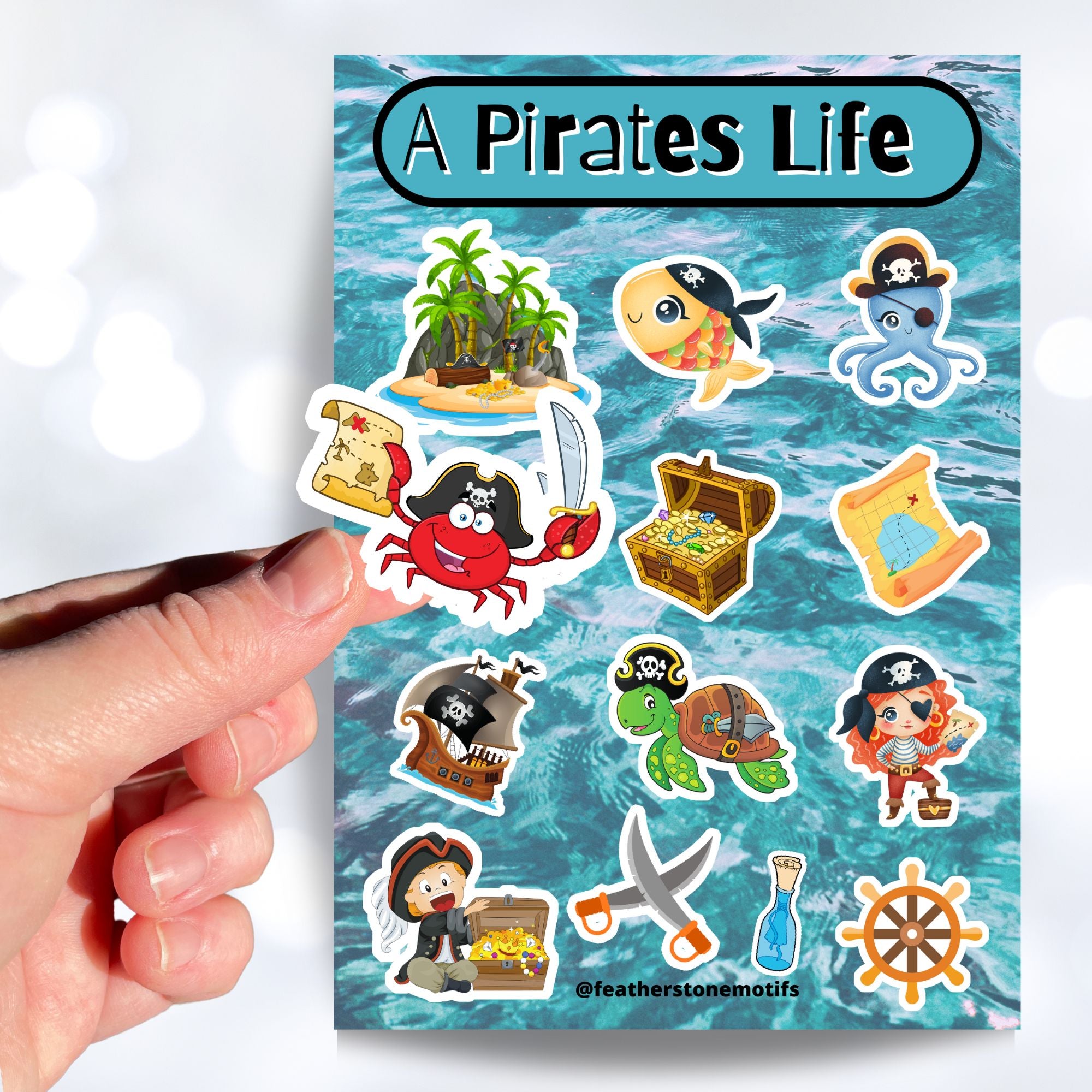 You'll walk the plank to get our A Pirates Life sticker sheet with individual stickers of treasure chests, treasure maps, pirate ships, pirates, and pirate creatures.  This is an image of a hand holding one of the stickers above the sticker sheet.