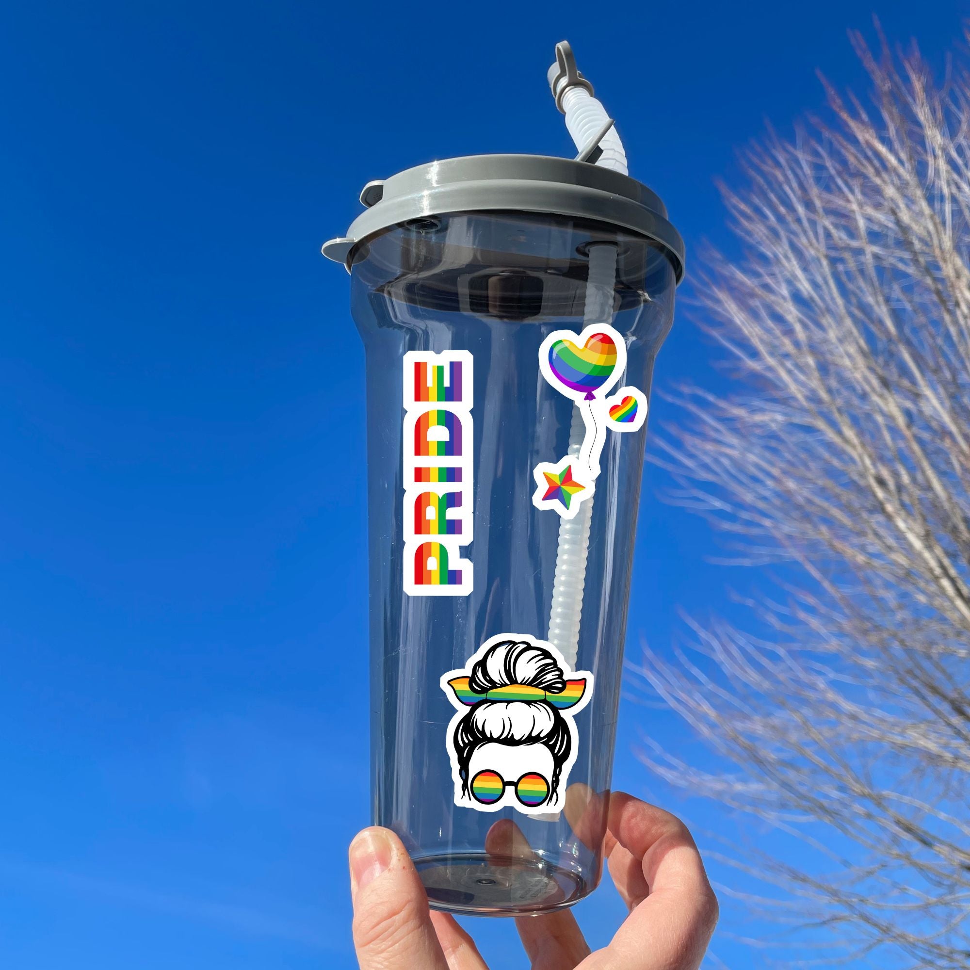 Show your LGBTQ Pride with this sticker sheet! This sticker sheet is filled with rainbow Pride images that are perfect for anywhere you want to show your Pride. This image is of a water bottle with a large Pride sticker along with a rainbow heart balloon sticker and a sticker of a woman's head with rainbow glasses and a rainbow bow in her hair.