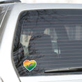 Load image into Gallery viewer, This individual die-cut sticker features a heart shape with graduated colors from orange at the top to blue at the bottom, and the word love written across. Perfect for the people you love! This image shows the Love Heart sticker on the back window of a car.
