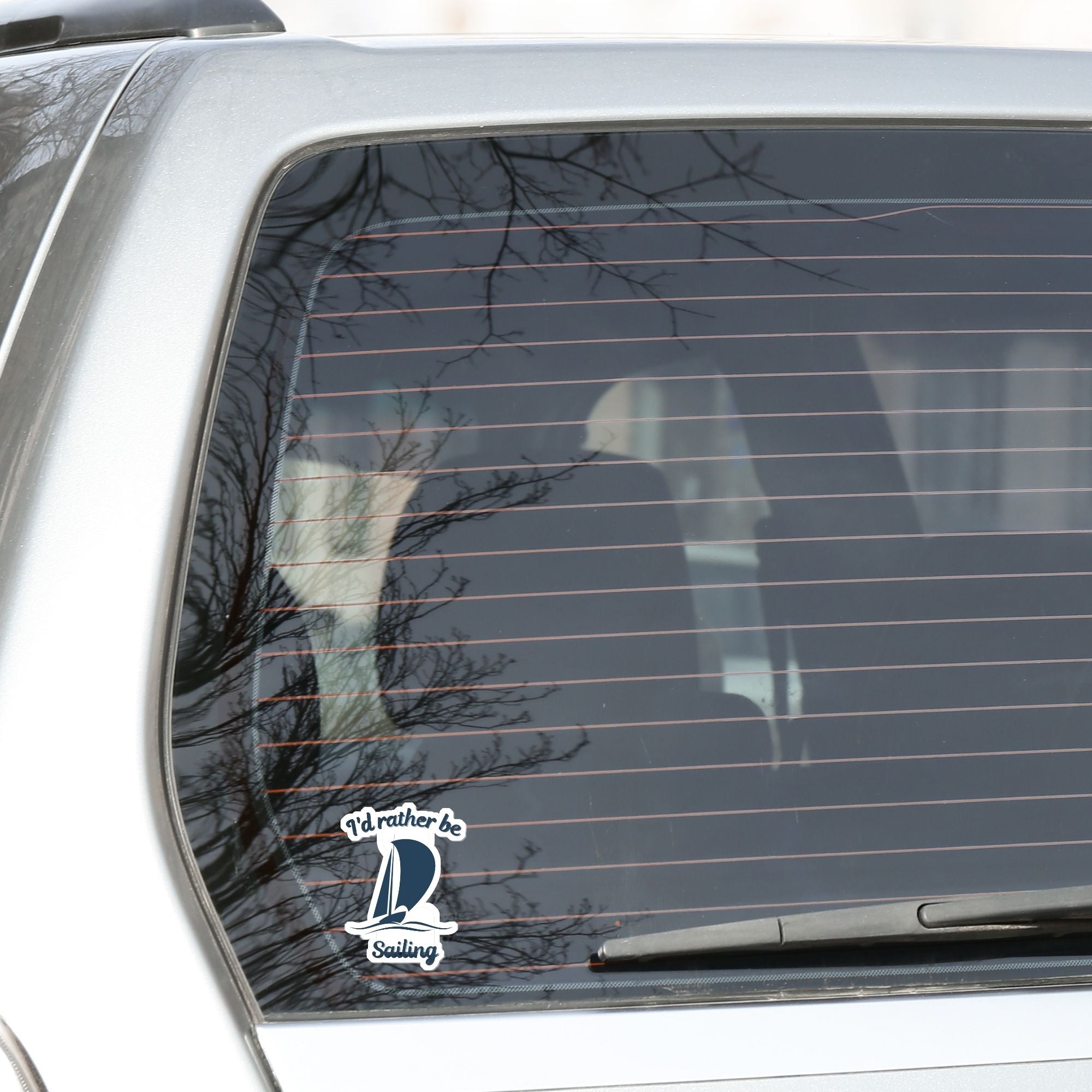 This individual die-cut sticker is great for anyone who loves to sail! It features a blue sailboat with the words "I'd rather be Sailing". This sailing sticker is understated, but says a lot! This image shows the I'd rather be Sailing die-cut sticker on the back window of a car.