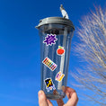 Load image into Gallery viewer, Reading, writing, and arithmetic; this sticker sheet is perfect for students, or educators, of all ages! It's filled with stickers showing all aspects of school - books, globe, crayons, backpacks, and of course a mortarboard / graduation cap! This image is of a water bottle with 5 stickers applied to it: "Well Done", an apple, crayons, pencils, and an easel with a painting.
