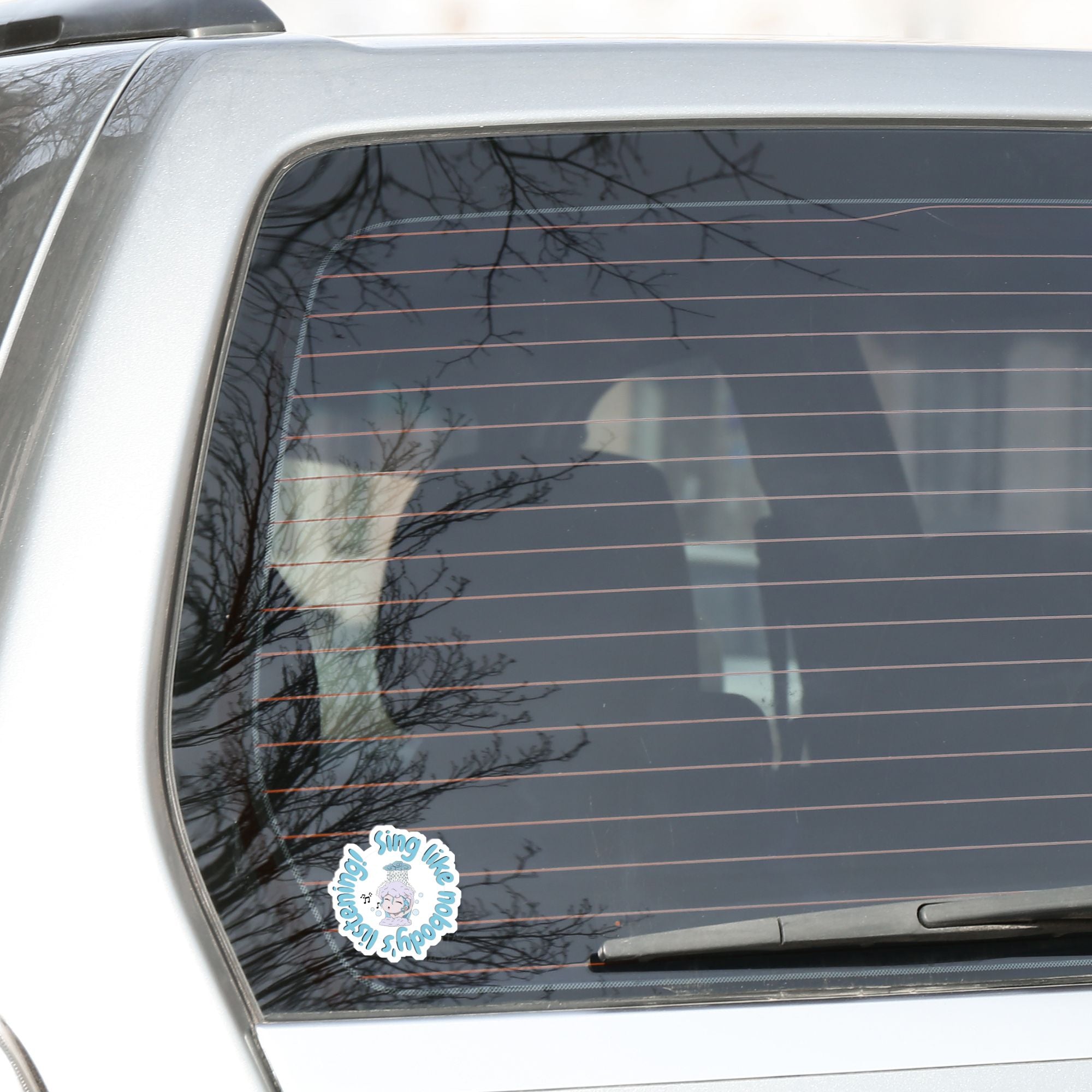 Sing like nobody's listening; dance like nobody's watching. This blue, gray, and white individual die-cut sticker features someone singing in the shower. This image shows the Sing like nobody's listening die-cut sticker on the back window of a car.