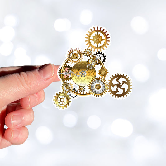 Nothing is more iconic for steampunk than gears and clocks. The steampunk gears individual die-cut sticker is a classic steampunk type image with gears and clocks. This image shows a hand holding the steampunk gears sticker.