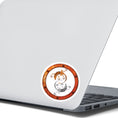 Load image into Gallery viewer, This round individual die-cut sticker features a rusty ring with screws on a white background with two mechanical geckos, one silver and one rust colored, in a yin-yang configuration. This image shows the steampunk geckos sticker on the back of an open laptop.
