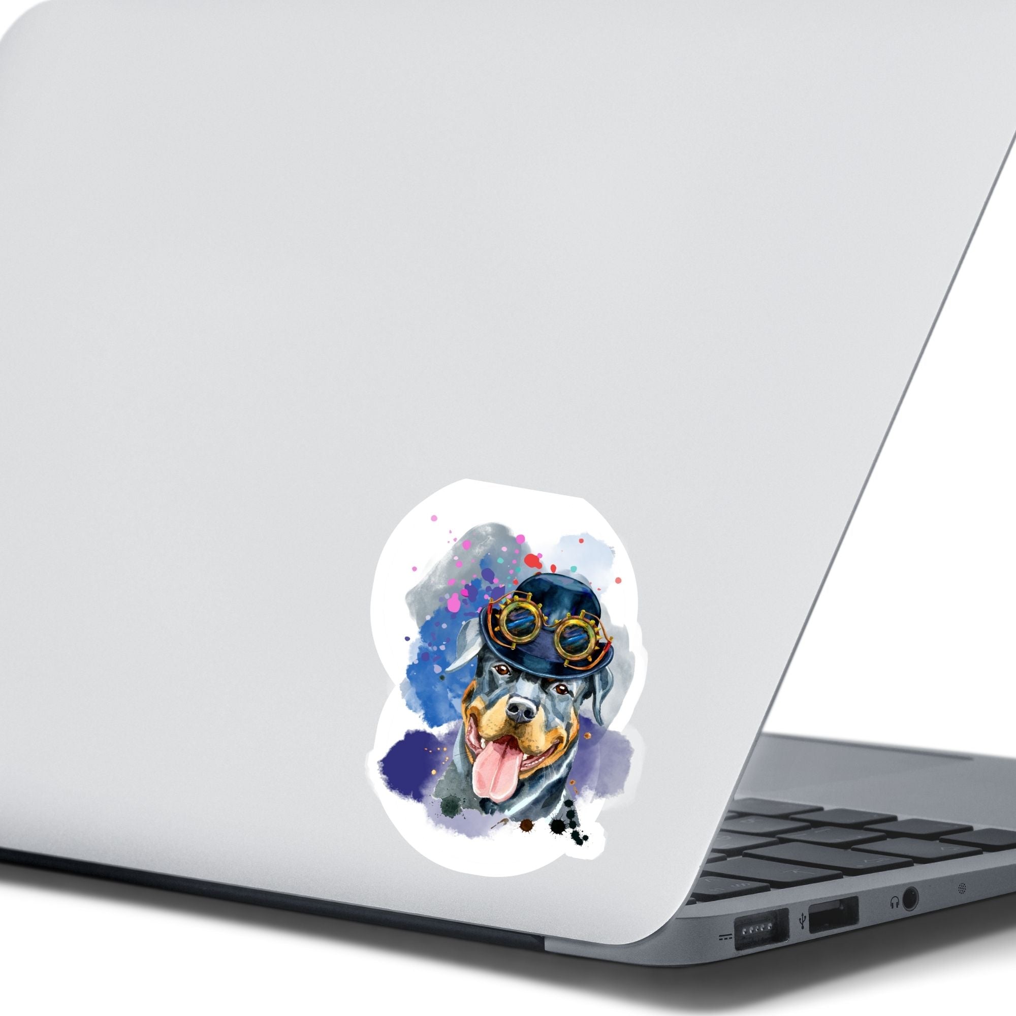 Steampunk Rotty is a happy looking Rottweiler with a steampunk hat and goggles, all on a pastel background. This image shows the steampunk Rotty sticker on the back of an open laptop.