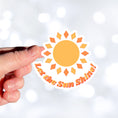Load image into Gallery viewer, Let the Sun Shine! This bright and fun individual die-cut sticker features a yellow and orange sun with the words "Let the Sun Shine!" below. This image shows a hand holding the Let the Sun Shine! sticker.
