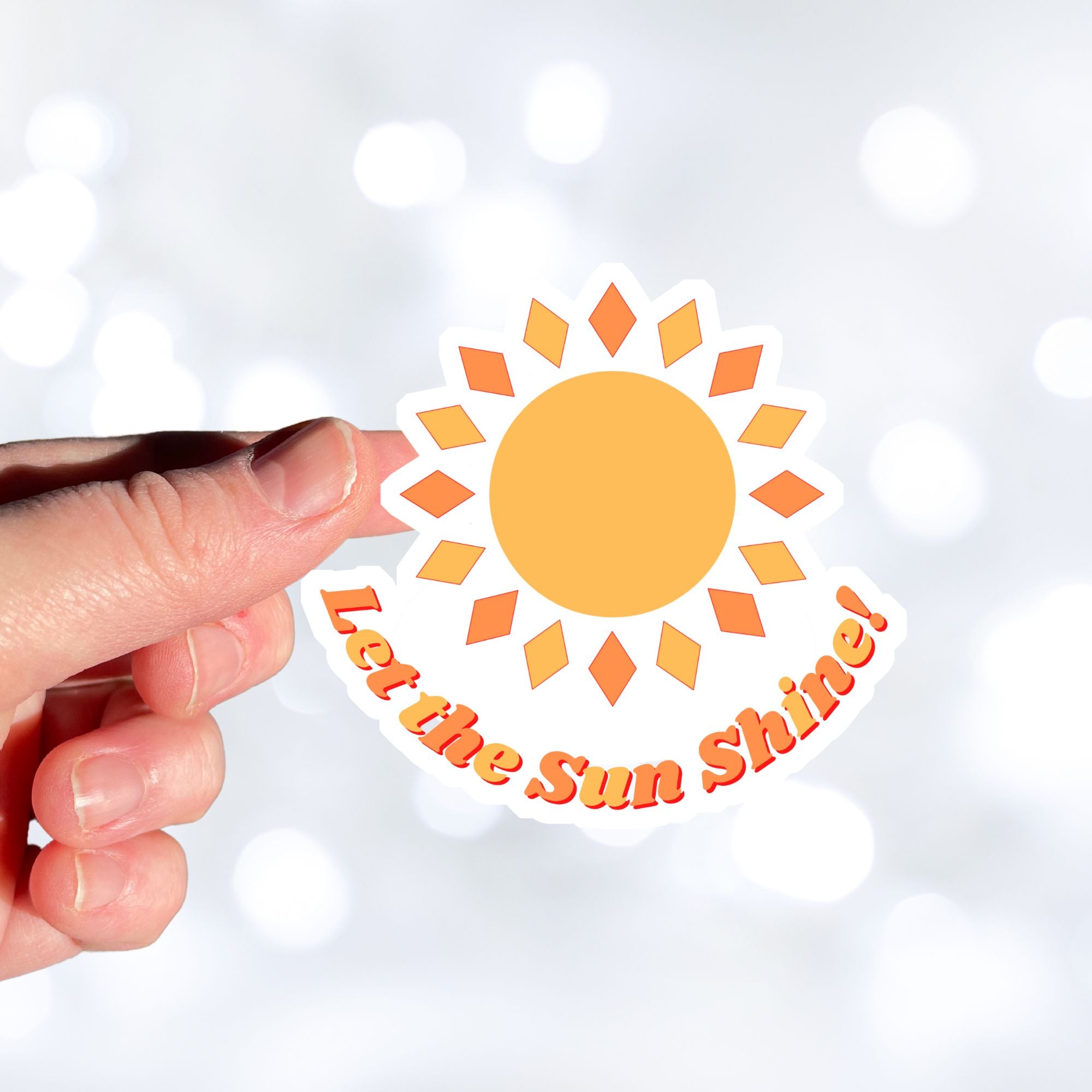 Let the Sun Shine! This bright and fun individual die-cut sticker features a yellow and orange sun with the words "Let the Sun Shine!" below. This image shows a hand holding the Let the Sun Shine! sticker.