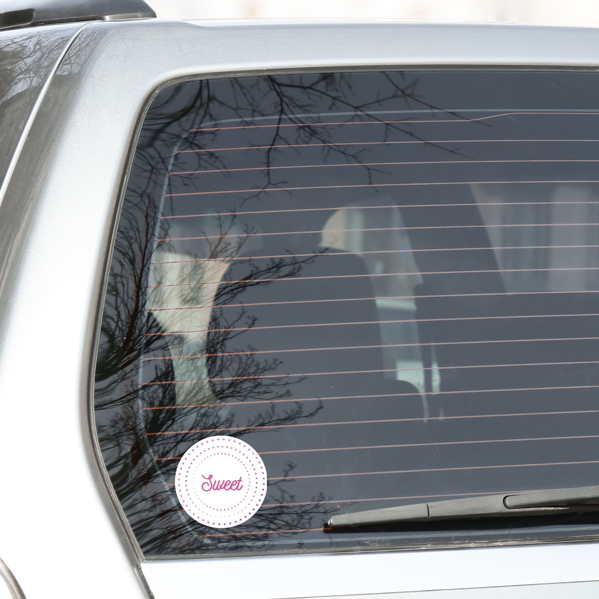 This round individual die-cut sticker is Sweet! It features the word Sweet in the center surrounded by pink and purple circular dots. This makes a great gift for anyone you're sweet on! This image shows the Sweet sticker on the back window of a car.