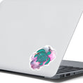 Load image into Gallery viewer, his individual die-cut sticker features a green tribal style turtle on a gray and pink cloudy background. This image shows the turtle sticker on the back of an open laptop.
