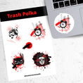 Load image into Gallery viewer, Trash Polka uses red, black, and white with a combination of abstract, surrealistic, and realistic images. This sticker sheet has four larger stickers from our die-cut sticker collection combined with a smaller sticker of a raven flying across a red sun. The stickers are the Trash Polka Woman's face, Trash Polka Clock, Trash Polka Owl, and Trash Polka Sugar Skull Woman. This image shows the sticker sheet next to an open laptop with the Trash Polka Clock sticker applied below the keyboard.
