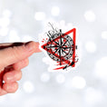 Load image into Gallery viewer, Trash Polka uses red, black, and white with a combination of abstract, surrealistic, and realistic images, and this individual die-cut sticker features a compass inside a red triangle outline on a white background. This image shows a hand holding the trash polka compass sticker.

