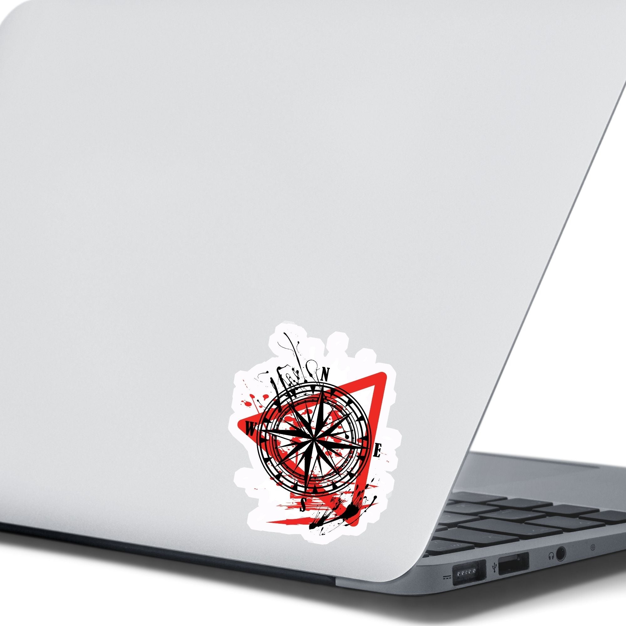 Trash Polka uses red, black, and white with a combination of abstract, surrealistic, and realistic images, and this individual die-cut sticker features a compass inside a red triangle outline on a white background. This image shows the trash polka compass sticker on the back of an open laptop.