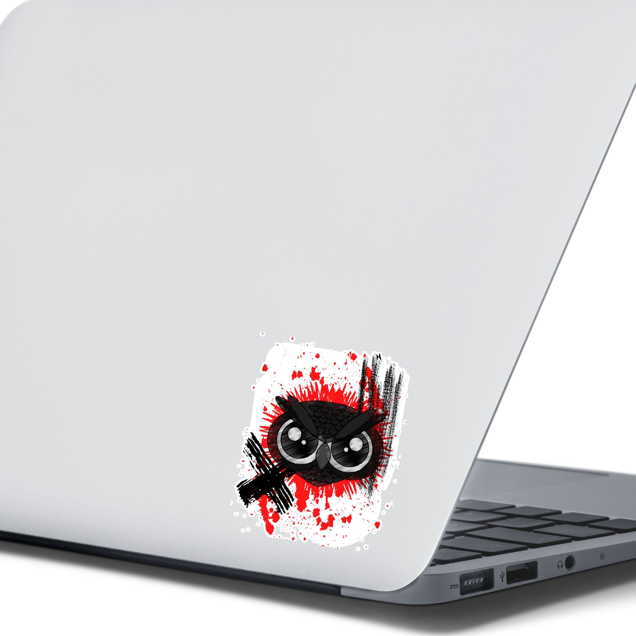 Trash Polka uses red, black, and white with a combination of abstract, surrealistic, and realistic images, and this individual die-cut sticker features a black owl face on a red and white background. This image shows the trash polka owl sticker on the back of an open laptop.
