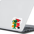 Load image into Gallery viewer, I wouldn't trust this space alien! This individual die-cut sticker features a green space alien flashing a peace sign, but wearing a chefs hat and trying to hide a wooden spoon, with a boiling pot behind, all on an orange background with the words "Trust Me!" in the upper right corner. This image shows the trust me alien sticker on the back of an open laptop.
