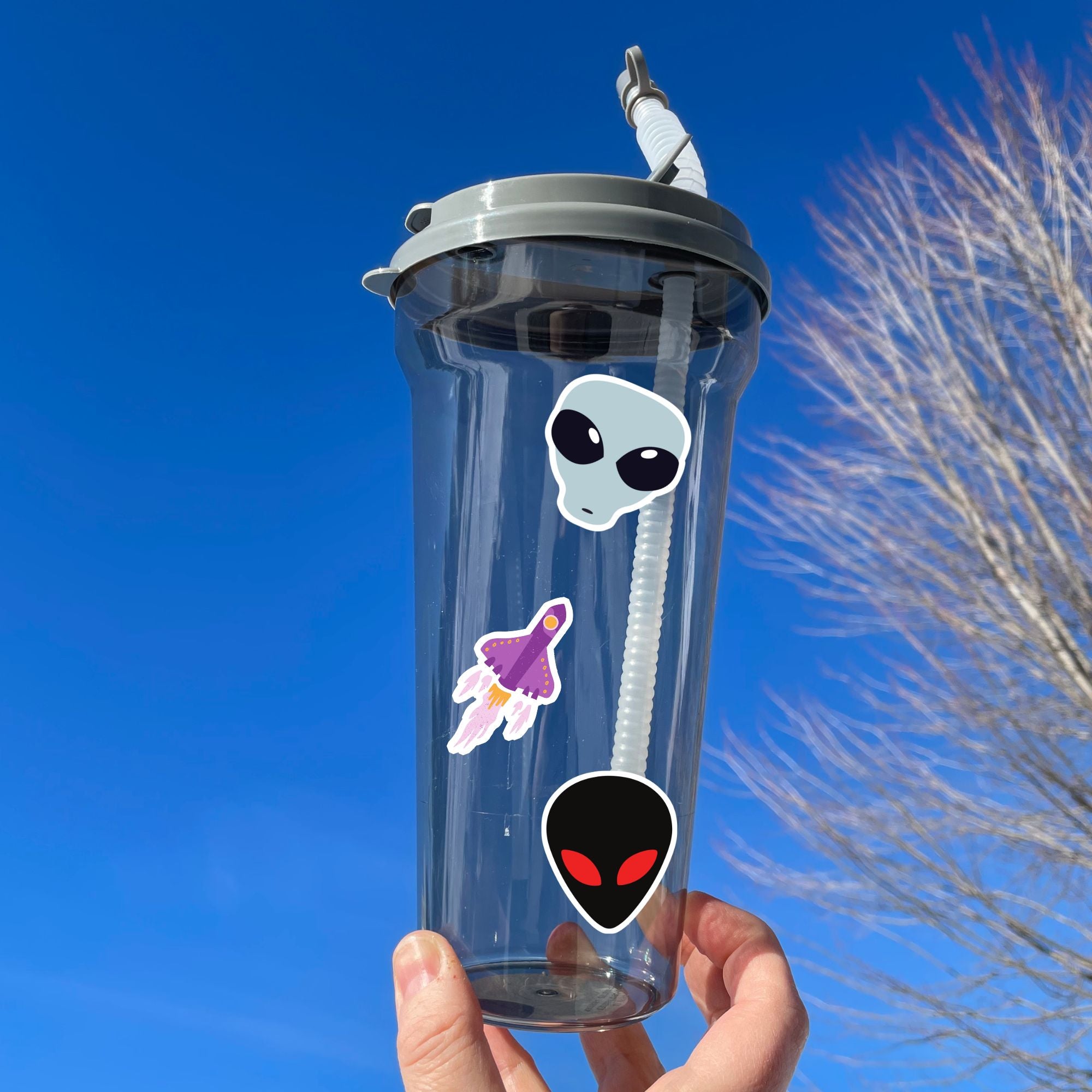 This sticker sheet is filled with aliens and UFOs with individual stickers of aliens, space ships, and alien creatures. This image is of a water bottle with some of the individual stickers on it.