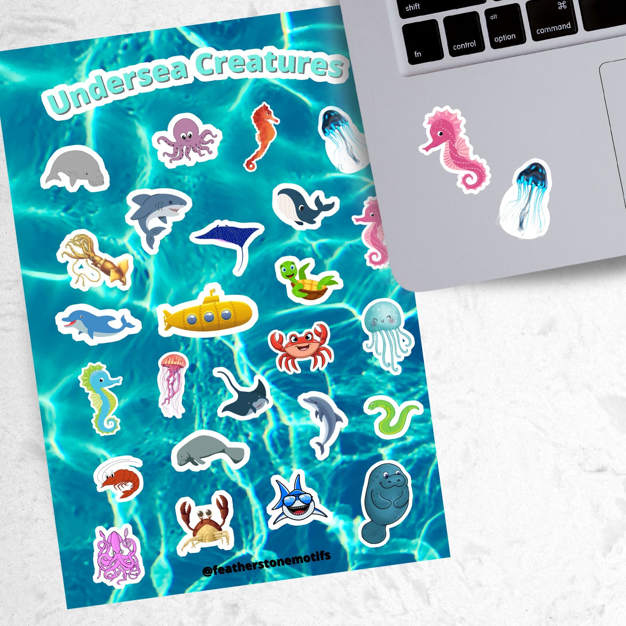 This sticker sheet is filled with fun and cute sticker images of all your favorite undersea creatures! Images include whales, sharks, jellyfish, manatee's, and crabs. There's even a yellow submarine! This image shows a pink seahorse sticker, and a blue jellyfish sticker, applied below the keyboard.
