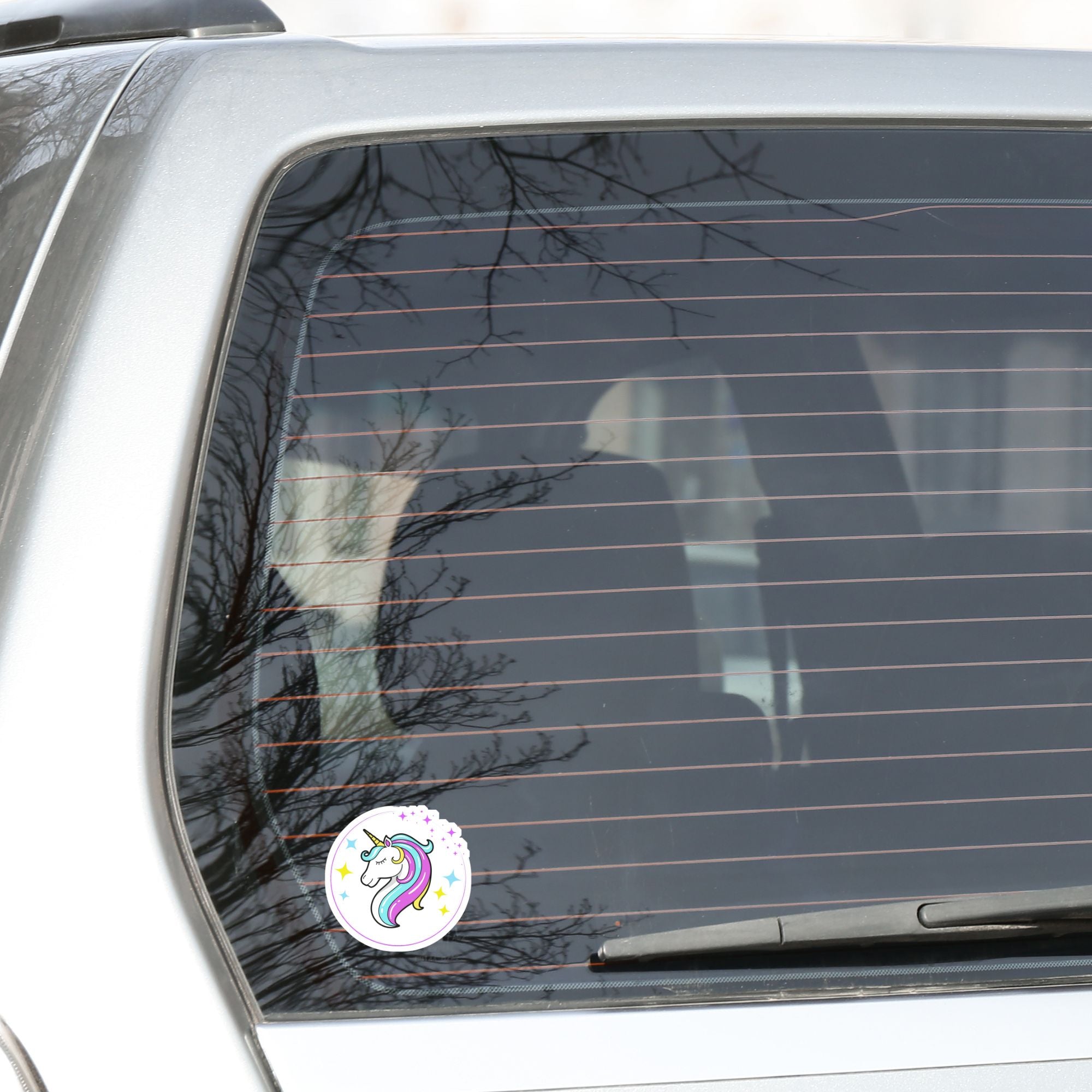 This individual die-cut sticker features a teal and purple unicorn with stars in the background. This image shows the teal and purple Unicorn sticker on the back window of a car.