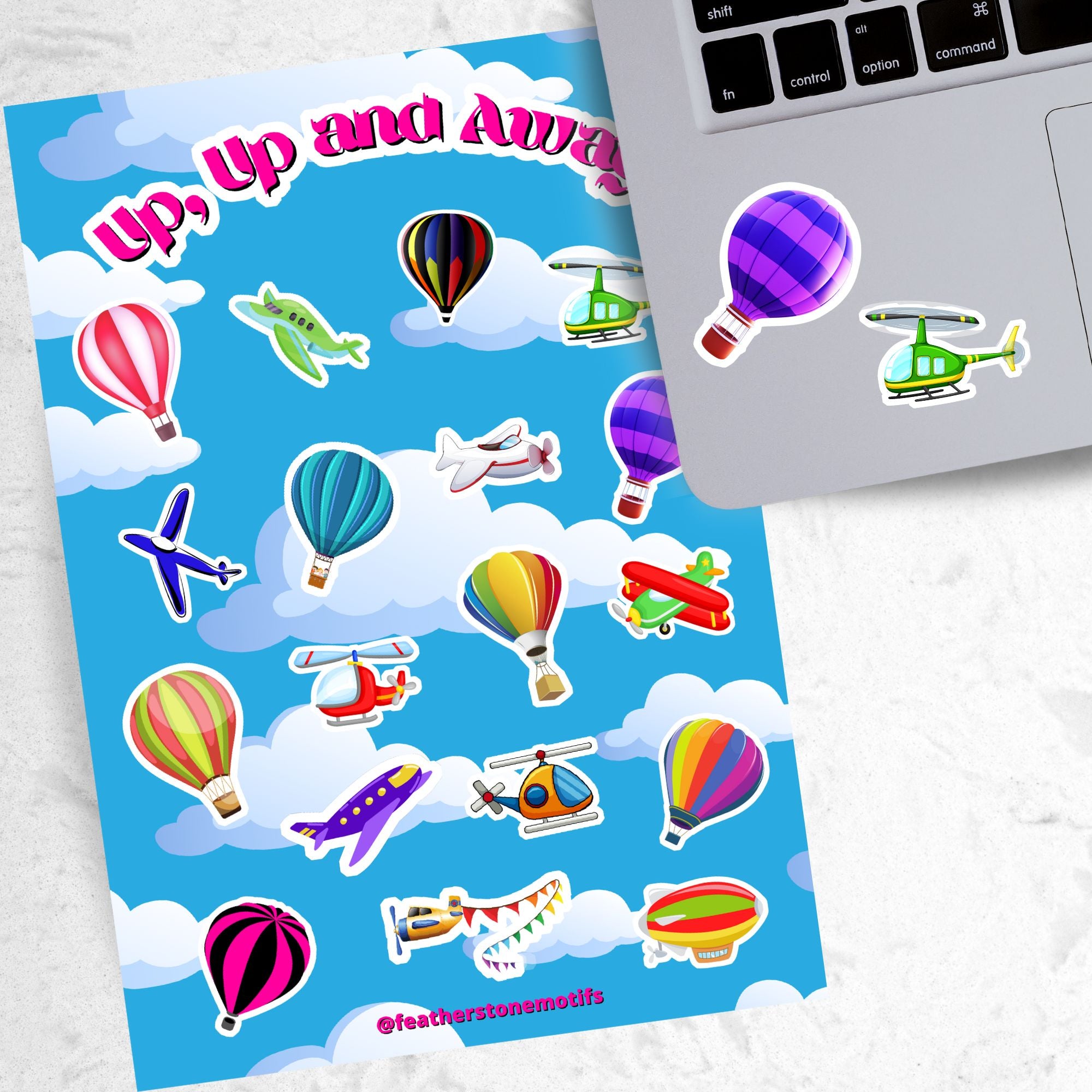 Fly away in a hot air balloon, a plane, or a helicopter with this sticker sheet. This image show the sticker sheet next to an open laptop with stickers of a purple hot air balloon, and a green helicopter, applied below the keyboard.