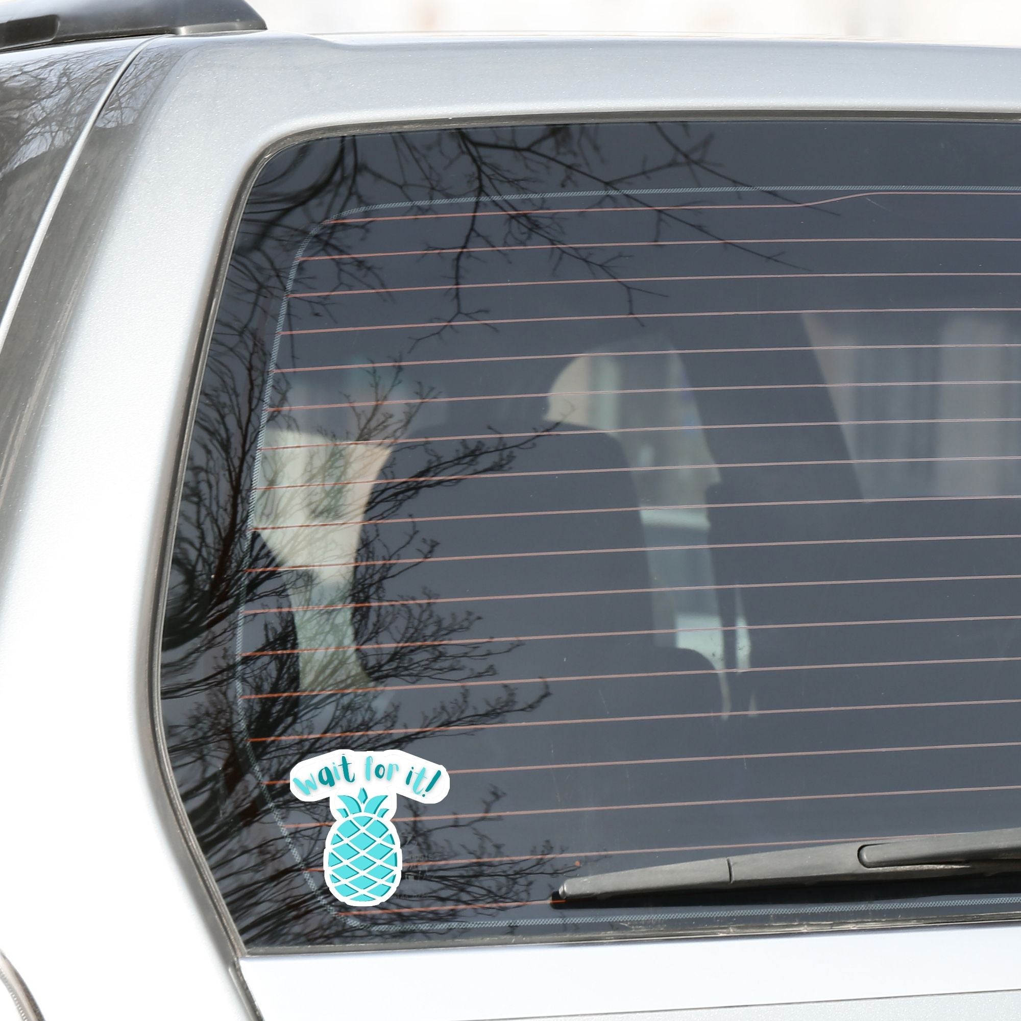 Don't get psyched out by this individual die-cut sticker! It features a teal blue pineapple with the words "Wait for it!" above. This image shows the Wait for it! die-cut sticker on the back window of a car.