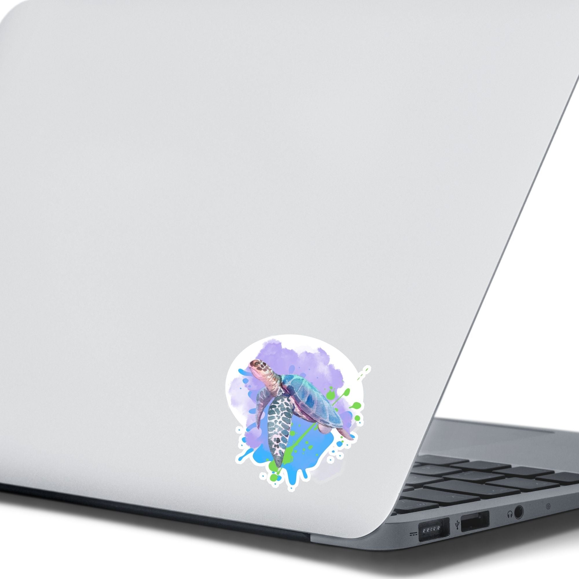 This individual die-cut sticker has a serene looking green sea turtle on a blue and purple background with splash of green. Just looking at this image is relaxing! This image shows the Watercolor Sea Turtle die-cut sticker on the back of an open laptop.